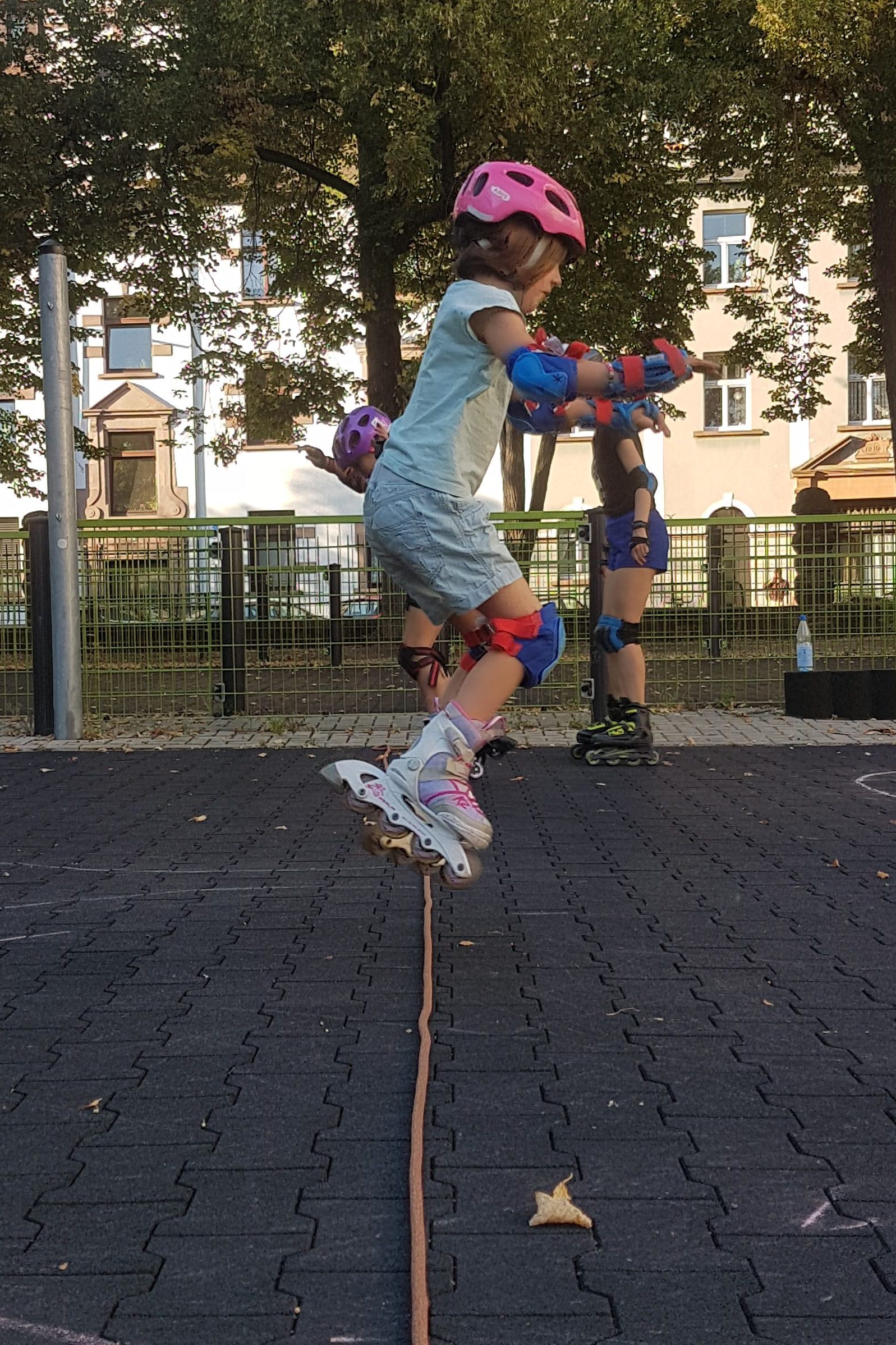 Kind springt mit Inlinern über ein Hindernis